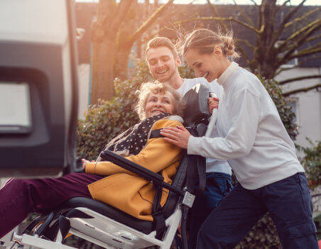 helpers picking up elderly woman for transport
