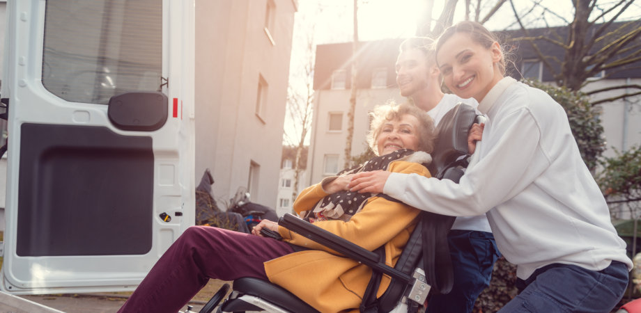 people assisting an elderly woman to get on the car